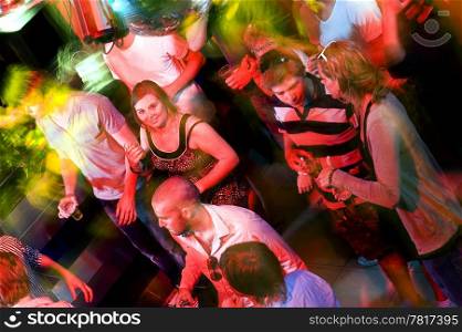 Girl smiling at the camera on a crowdy dance floor in a discotheque