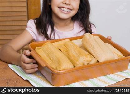 Girl smiling with a tray of breads in the kitchen