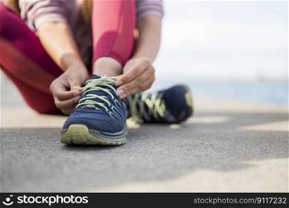 girl soprtsman sits on the pavement and ties shoelaces on sneakers