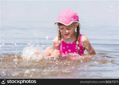 Girl splashing in cap sitting on a shelf in water