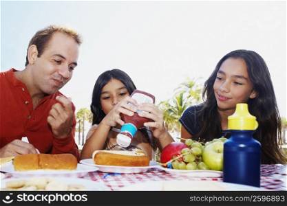 Girl squeezing ketchup from a bottle on a hot dog