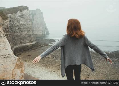 girl standing at the edge of rock in the Etretat. France