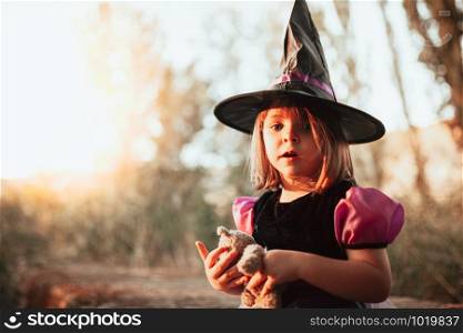 Girl standing disguised as a witch in the woods during Halloween