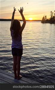 Girl standing on a boardwalk with her arms raised, Lake of the Woods, Ontario, Canada
