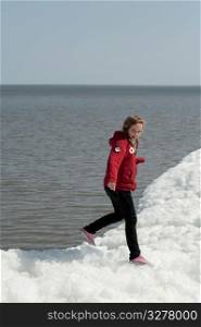 Girl standing on a pile of snow at Winnipeg Beach, Manitoba, Canada