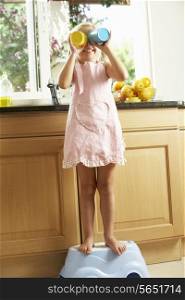 Girl Standing On Plastic Step In Kitchen Helping With Washing Up
