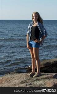 Girl standing on rock overlooking Atlantic Ocean, Cavendish Beach, Green Gables, Prince Edward Island, Canada