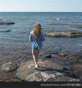 Girl standing on rocks along Cavendish Beach, Green Gables, Prince Edward Island, Canada