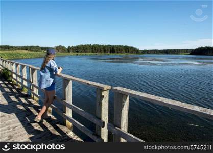 Girl standing on wooden bridge at Cavendish Dunelands Trail, Green Gables, Prince Edward Island, Canada
