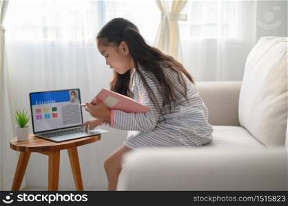 girl student sitting at the table, writing homework . Teen using laptop computer to study.New normal.Social distancing.stay home