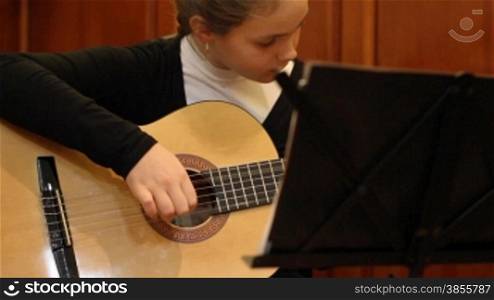 girl studies to play a guitar.
