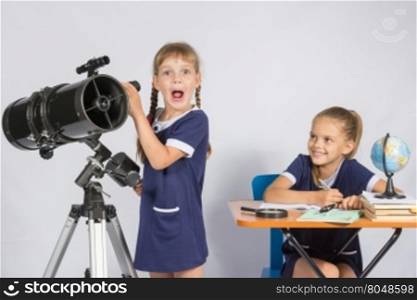 Girl surprised astronomer observing through a telescope, the other girl looked at her