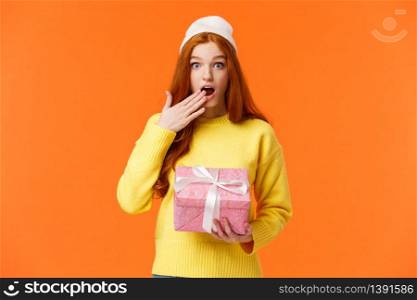 Girl surprised didnt expact gift from you. Amused and startled cute redhead girlfriend open mouth, cover it with hand as receive cute pink box of present, look camera excited, orange background.. Girl surprised didnt expact gift from you. Amused and startled cute redhead girlfriend open mouth, cover it with hand as receive cute pink box of present, look camera excited, orange background
