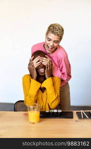 Girl surprising her female best friend. Model covering her eyes and hugging from behind. Two surprised girls. Women having fun and showing face emotions