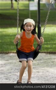 Girl swinging on a chain swing ride and smiling
