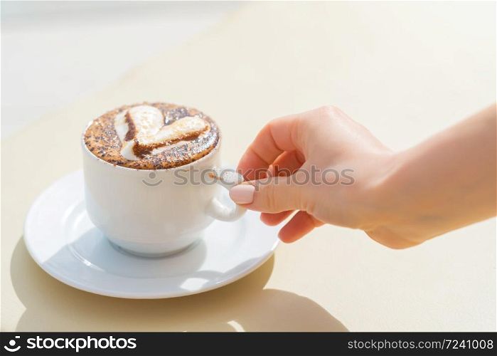 Girl take a white cup of coffee with milk and decorative heart on a deck chair near the pool. Perfect morning on vacation concept. Girl take a white cup of coffee with milk and decorative heart on a deck chair near the pool. Perfect morning on vacation concept.