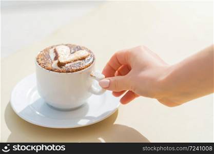 Girl take a white cup of coffee with milk and decorative heart on a deck chair near the pool. Perfect morning on vacation concept. Girl take a white cup of coffee with milk and decorative heart on a deck chair near the pool. Perfect morning on vacation concept.