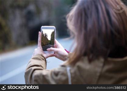 girl taking a photo on a smartphone in the Cheile Bicazului, Romania