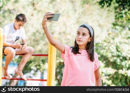 girl taking a selfie with her cell phone in a park