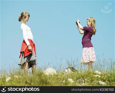 Girl taking picture of friend outdoors