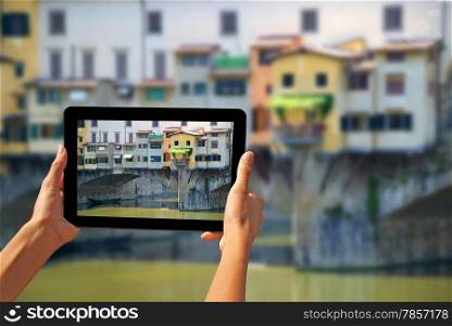 Girl taking pictures on a tablet Ponte Vecchio is a famous medieval bridge over the River Arno in Florence, Italy