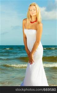 Girl taking walk on shore. Young elegant woman in white dress. Outdoor leisure relax concept. . Girl taking walk on shore.