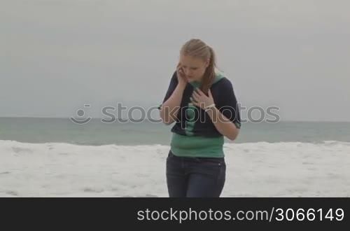 Girl talking on phone at the beach, middle shot.