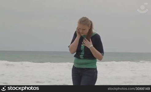 Girl talking on phone at the beach, middle shot.