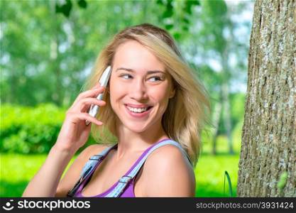 girl talking on the phone near a tree in the park