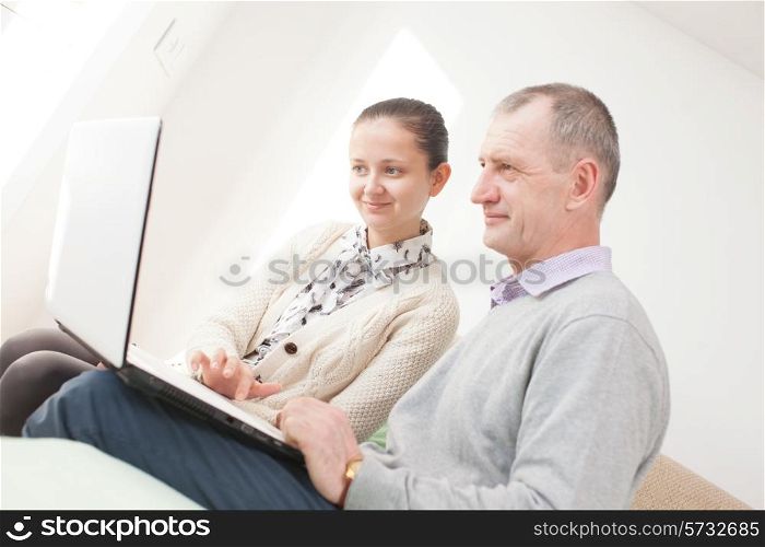 Girl teaching to use a laptop by senior man