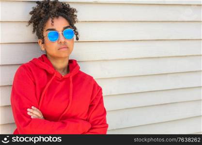 Girl teenager cool teen mixed race biracial African American female young woman wearing blue sunglasses and a red hoodie on vacation in summer sunshine