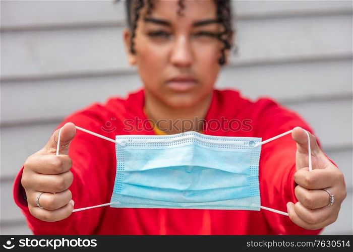 Girl teenager teen mixed race biracial African American female young woman holding face mask in Coronavirus COVID-19 pandemic