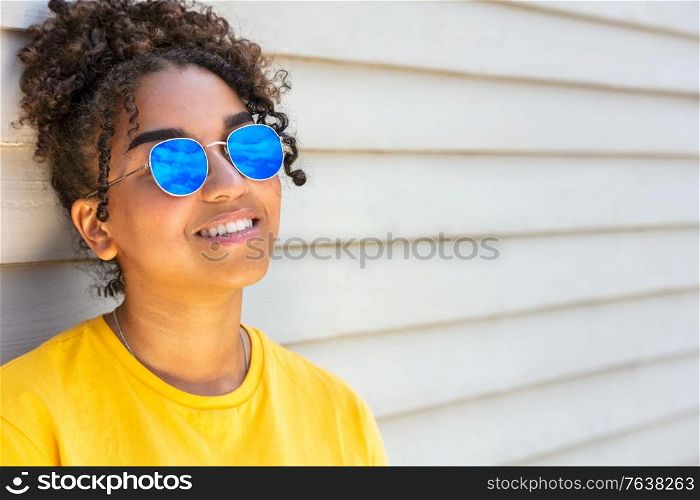 Girl teenager teen mixed race biracial African American female young woman wearing blue sunglasses smiling with perfect teeth on vacation in summer sunshine