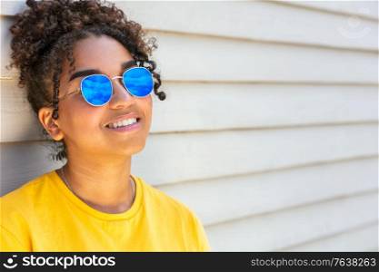 Girl teenager teen mixed race biracial African American female young woman wearing blue sunglasses smiling with perfect teeth on vacation in summer sunshine