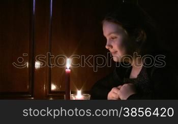 girl the teenager looks at a burning candle.