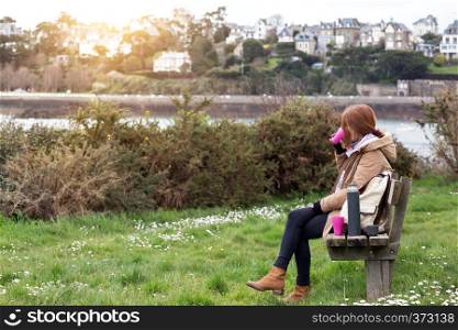 girl tourist rests on a bench and drinks tea