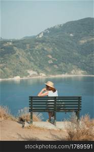 girl tourist sitting on a bench at the observation deck and looks at the sea and a beautiful landscape, Corfu Island in Greecethe sea