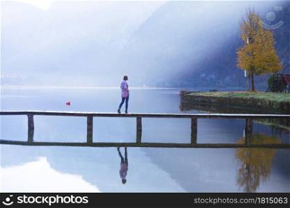 girl tourist stands on a wooden bridge on a mountain lake in the early morning. beautiful landscape and reflection