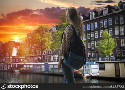 girl tourist with a backpack looking at the sunset in Amsterdam. Amsterdam autumn.
