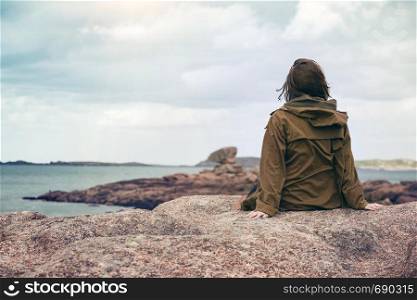 girl traveler sits on a beach near the sea and the shore at the Tregastel, Brittany. France