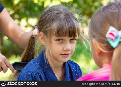 Girl trying to comb the girl&rsquo;s tightly tangled hair