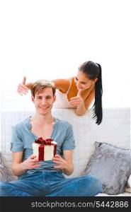 Girl uncover eyes to happy boyfriend with present in hand&#xA;