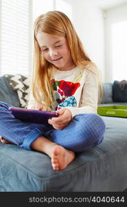 Girl using digital tablet on sofa in living room