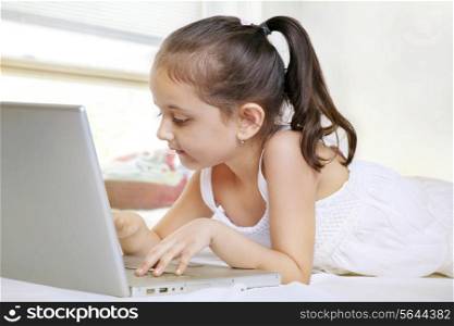 Girl using laptop while lying on bed