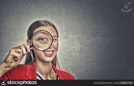 Girl using magnifier for search. Beautiful woman in red jacket looking through magnifying glass