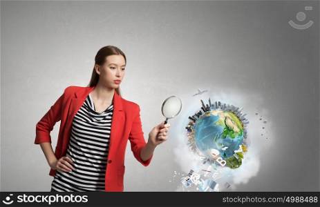 Girl using magnifier for search. Young attractive woman in red jacket looking in magnifying glass. Elements of this image are furnished by NASA