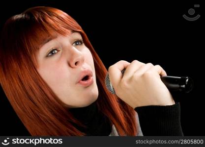 Girl using microphone, beautiful redhead with blue eyes. Studio shot.