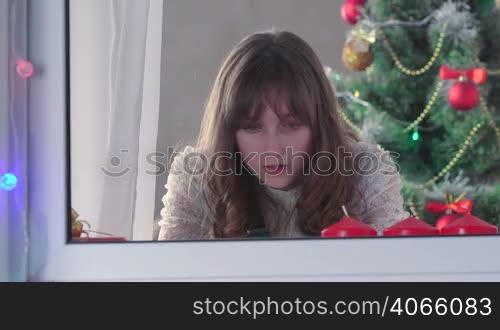 Girl using smart phone near Christmas tree something typing