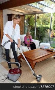 Girl vacuuming for an elderly woman