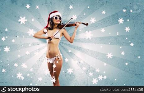 Girl violinist. Young Santa girl in bikini playing violin